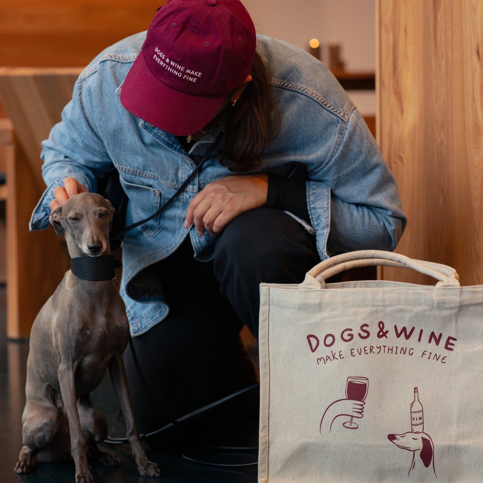 Person with a dog and a tote bag with 'Dogs & Wine' text in a casual setting